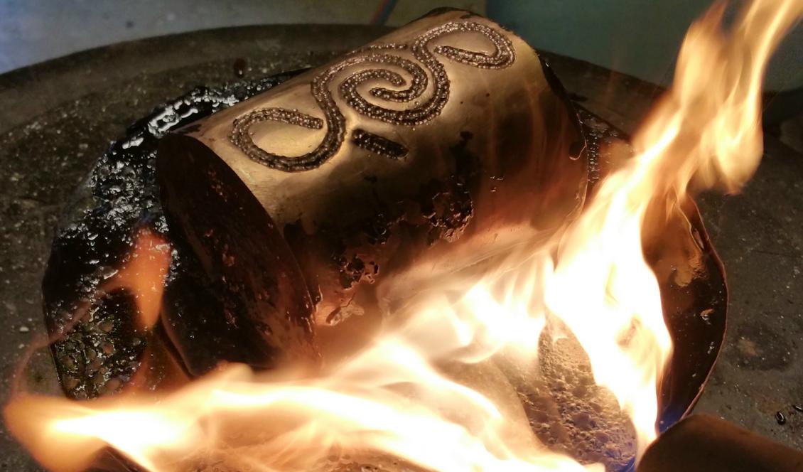 Kopparmuggen har fyllts och gjutits fast i Beck för att kunna ciseleras. Här bränns becket bort när ciseleringen är klar.