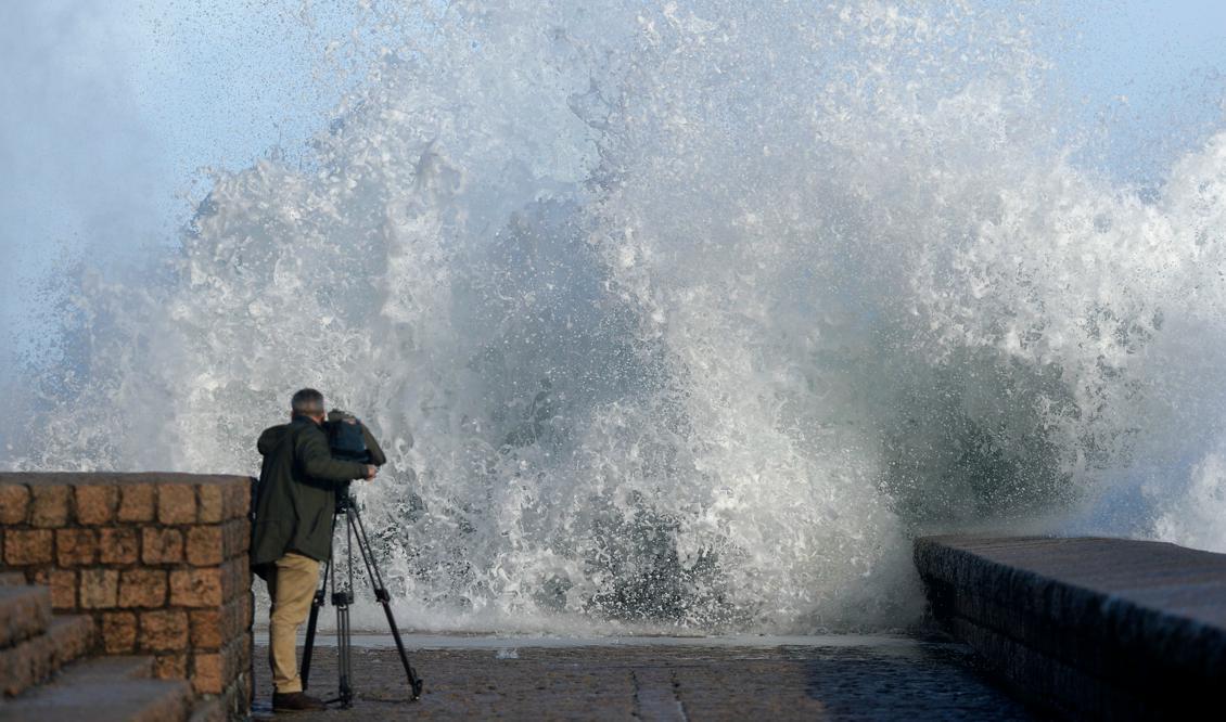 
En man filmar höga vågor som slår mot strandpromenaden i den baskiska staden San Sebastian. Varning för starka vindar, kraftiga regn och laviner har sänts ut till flera spanska regioner längs Atlantkusten. Foto: Ander Gillenea/AFP/Getty Images                                            