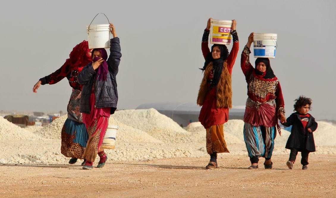 Några kvinnor hämtar vatten i ett nyöppnat läger nära Bab al-Hawa i Syrien, vid gränsen mot Turkiet. När familjer i södra Idlib och utanför staden Aleppo utsattes för militärt angrepp flydde många familjer hit. Foto: Ibrahim Yasouf/AFP/Getty Images