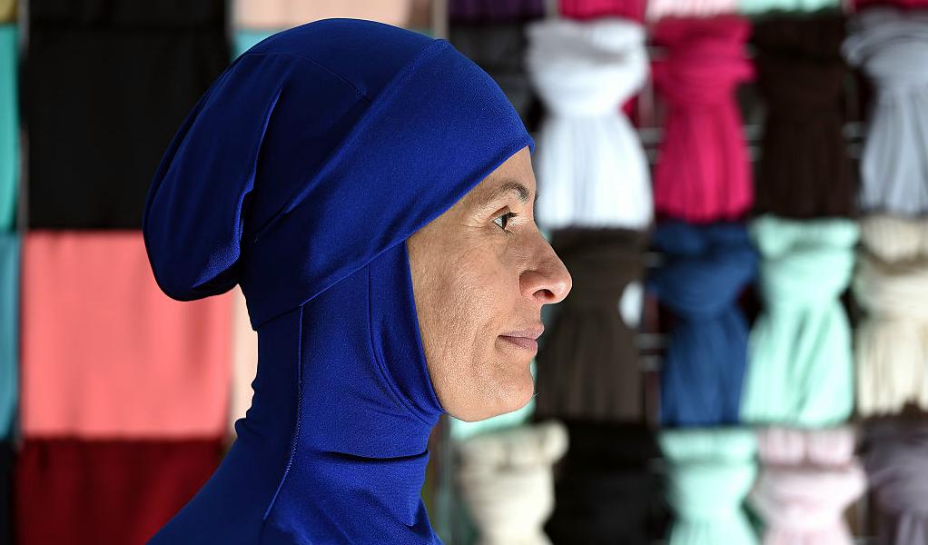 En muslimsk kvinna visar upp en burkini-dräkt i Sydney, Australien. Simdräkten har väckt debatt i många länder, då den ses som en symbol för kvinnoförtryck. I Australien ses den dock som en symbol för inkludering, säger burkinidesignern Aheda Zanetti till AFP. Foto: AFP/Saeed Khan