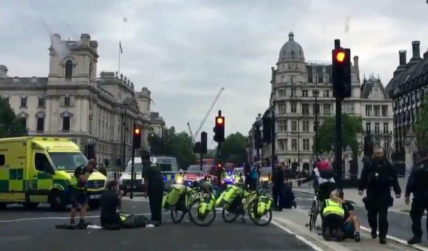 Ambulans och säkerhetspersonal utanför det brittiska parlamentet i London sedan en bil kraschat in i en säkerhetsbarriär. Foto: UK Newsflare/AP/TT