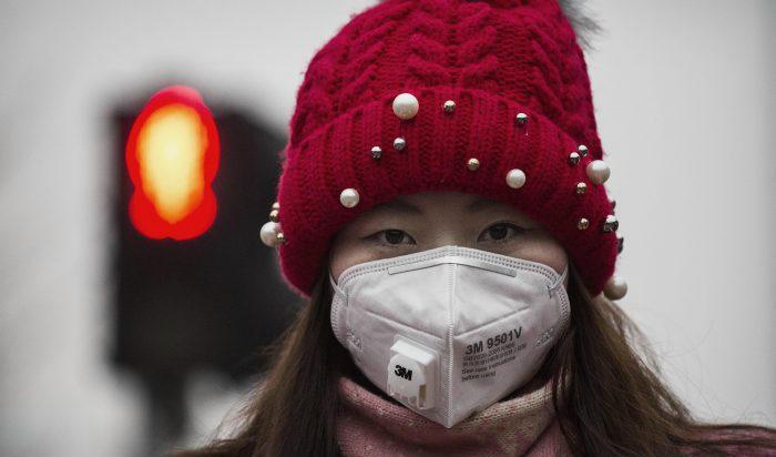 En kvinna i Hongkong som bär andningsmask till skydd mot luftföroreningar. Foto: Kevin Frayer/Getty Images
