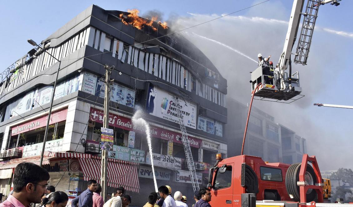 Räddningstjänsten bekämpar elden i flervåningshuset i Surat i västra Indien. Foto: Sarju Parekh/AP/TT