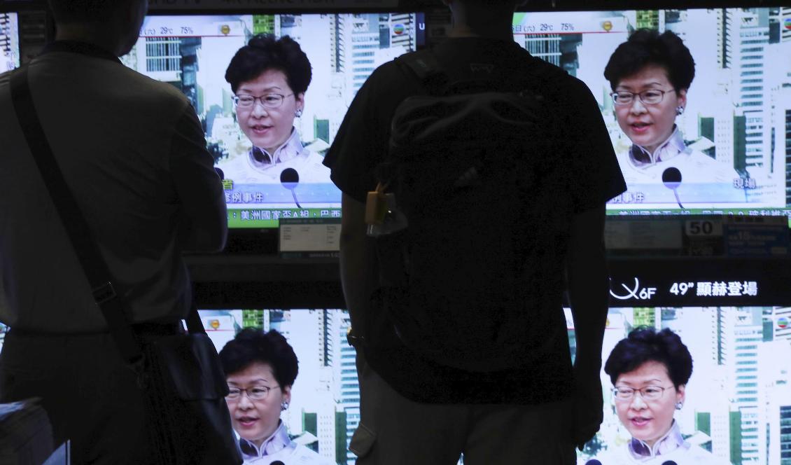 Hongkong-bor tittar på sändningen på lördagen då Carrie Lam meddelade att det omstridda lagförslaget pausas. Foto: Vincent Yu/AP/TT