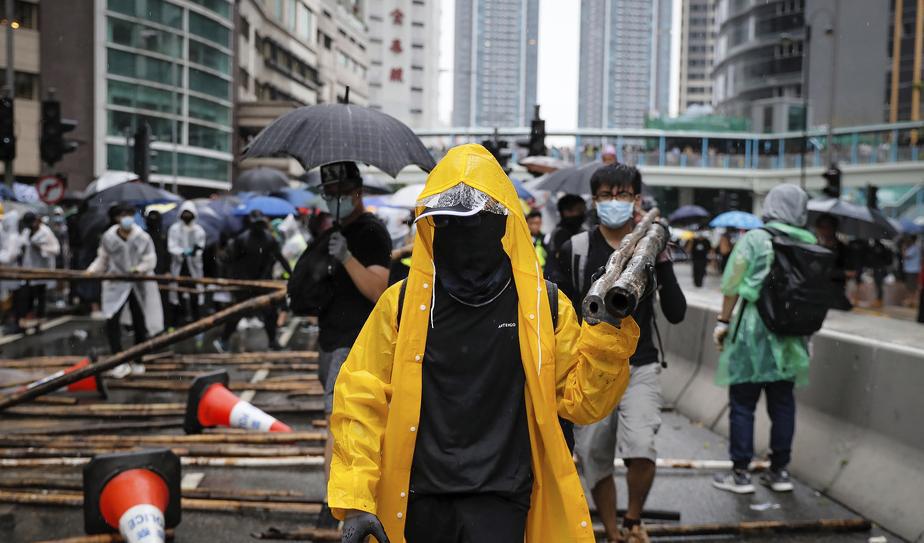Demonstrerande använder bambupinnar för att blockera en väg under söndagens protester. Foto: Kin Cheung/AP/TT