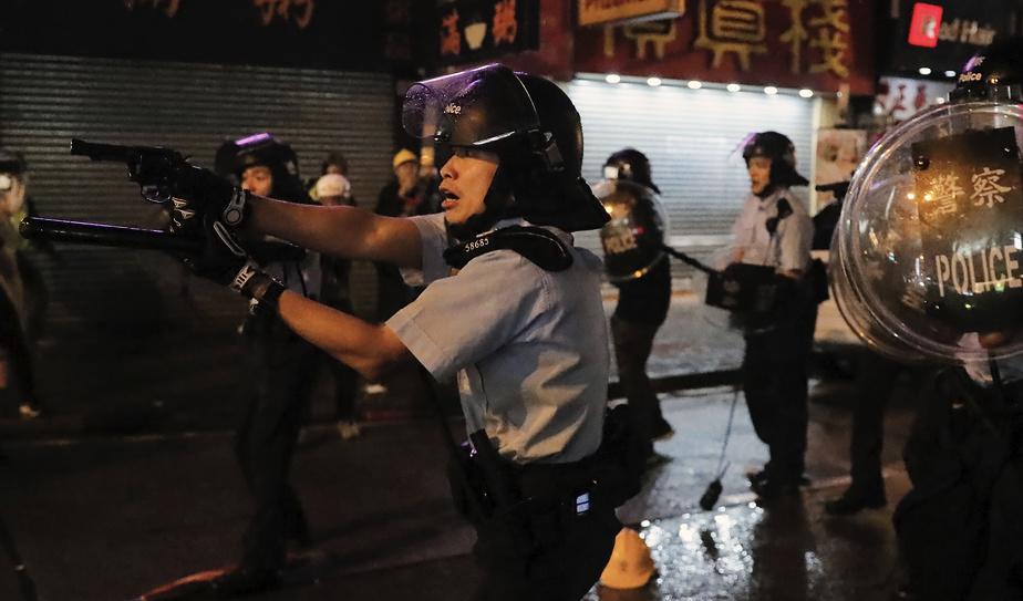 Flera poliser drog sina vapen under protesterna i Hongkong på söndagen. Minst ett skott har avlossats, enligt polisen. Foto: Kin Cheung/AP/TT