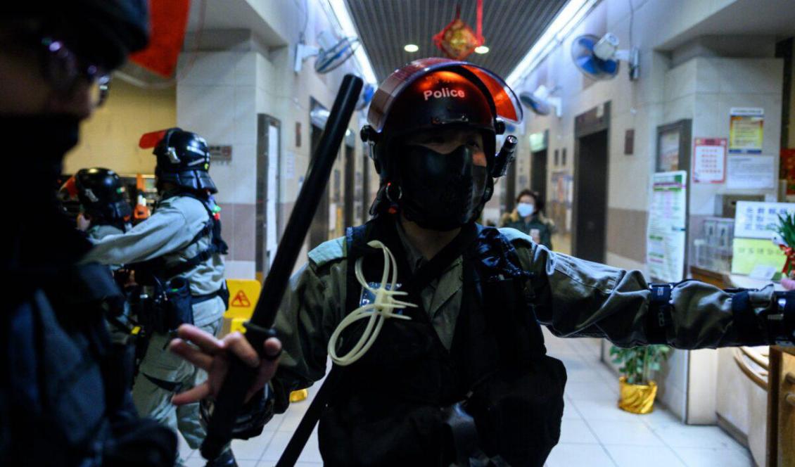 Kravallpoliser står i entrén till ett bostadshus där boende protesterar mot planerna om att en tom bostadsdel ska bli ett tillfälligt karantänläger för coronaviruspatienter. Foto: Philip Fong, AFP via Getty Images