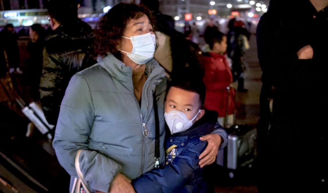 En kinesisk pojke kramar en släkting innan han ska stiga på ett tåg på Pekings tågstation i Peking, Kina, den 21 jan, 2020. Foto: Kevin Frayer, Getty Images