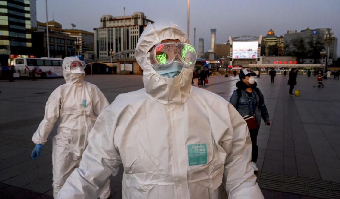 Människor bär skyddsmasker och skyddsdräkter när de anländer till Pekings tågstation den 13 mars, 2020. Foto: Kevin Frayer, Getty Images
