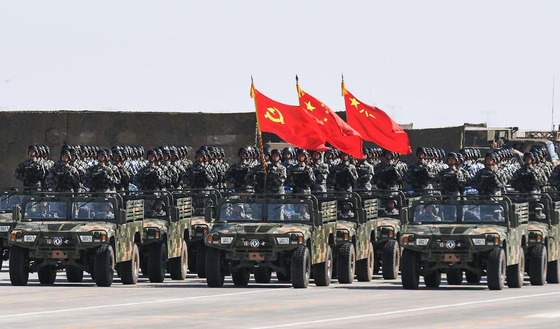 Kinesiska soldater bär kommunistpartiets, statens och Folkets befrielsearmés flaggor under en militärparad i inre Mongoliet i Kinas norra regioner, för att visa upp sin militärmakt, den 30 juli 2017. Foto: STR/AFP via Getty Images.