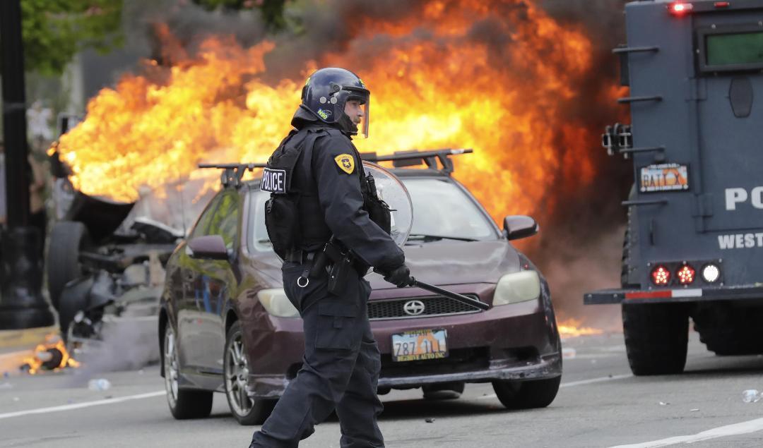 En polis bevakar en brinnande bil i Salt Lake City på lördagen. Foto: Rick Bowmer/AP/TT
