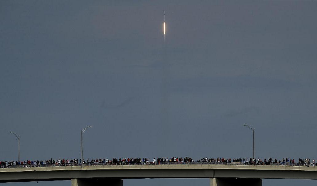 Raketuppskjutningar är ett folknöje i Florida, även i covidtider. Här beundrar samlade åskådare den stigande Falcon 9-raketen från en bro i Titusville. Foto: Charlie Riedel/AP/TT