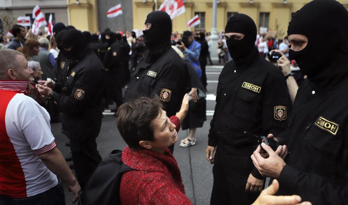Demonstranter framför maskerade kravallpoliser i centrala Minsk på söndagen. Foto: AP/TT
