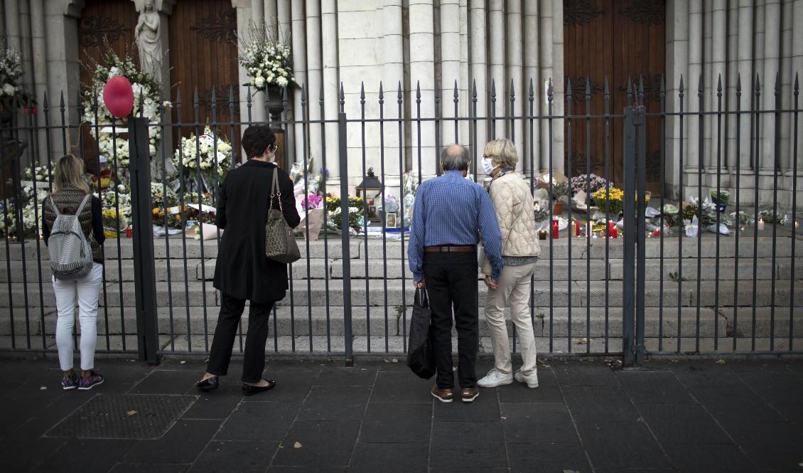 Folk ber framför Notre Dame i Nice. Foto: Daniel Cole