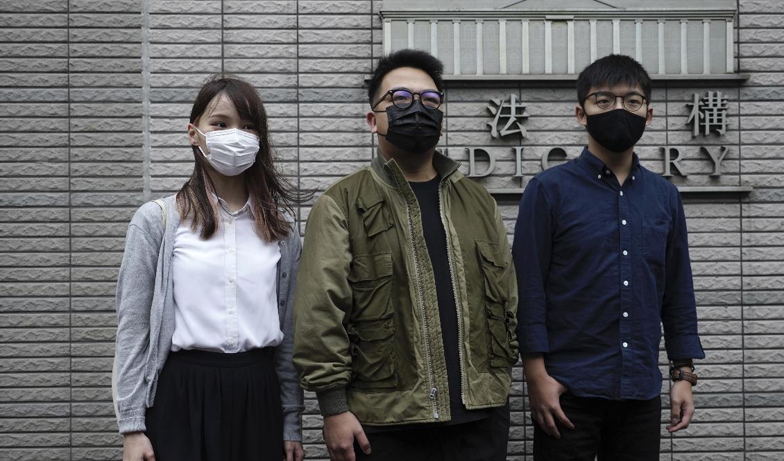 Joshua Wong (till höger) framför domstolsbyggnaden i Hongkong tillsammans med aktivisterna Ivan Lam och Agnes Chow den 23 november. Foto: Vincent Yu/AP/TT