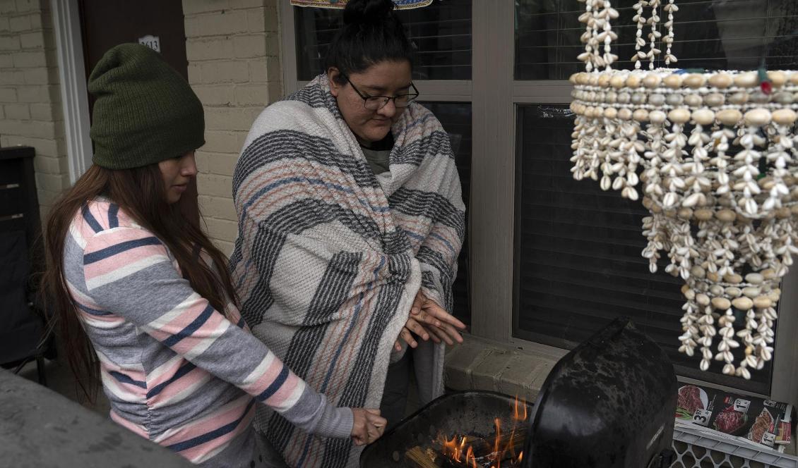 

Två Texasbor värmer sig på en utegrill i det kalla vädret, efter att strömmen gått under vinterstormen Uri, 16 februari 2021 i Houston, Texas. Foto: Kerem Yucel/AFP via Getty Images                                                                                        