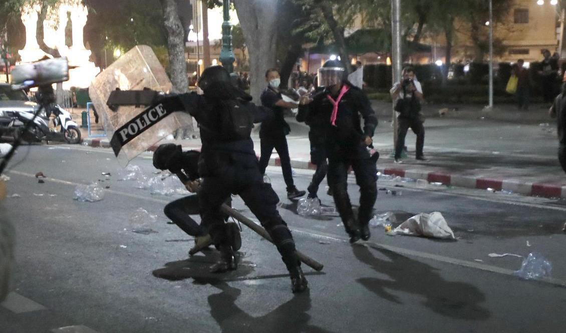 En kravallpolis drabbar samman med en demonstrant utanför kungliga palatset i Bangkok i Thailand på lördagen. Foto: Sakchai Lalit/AP/TT