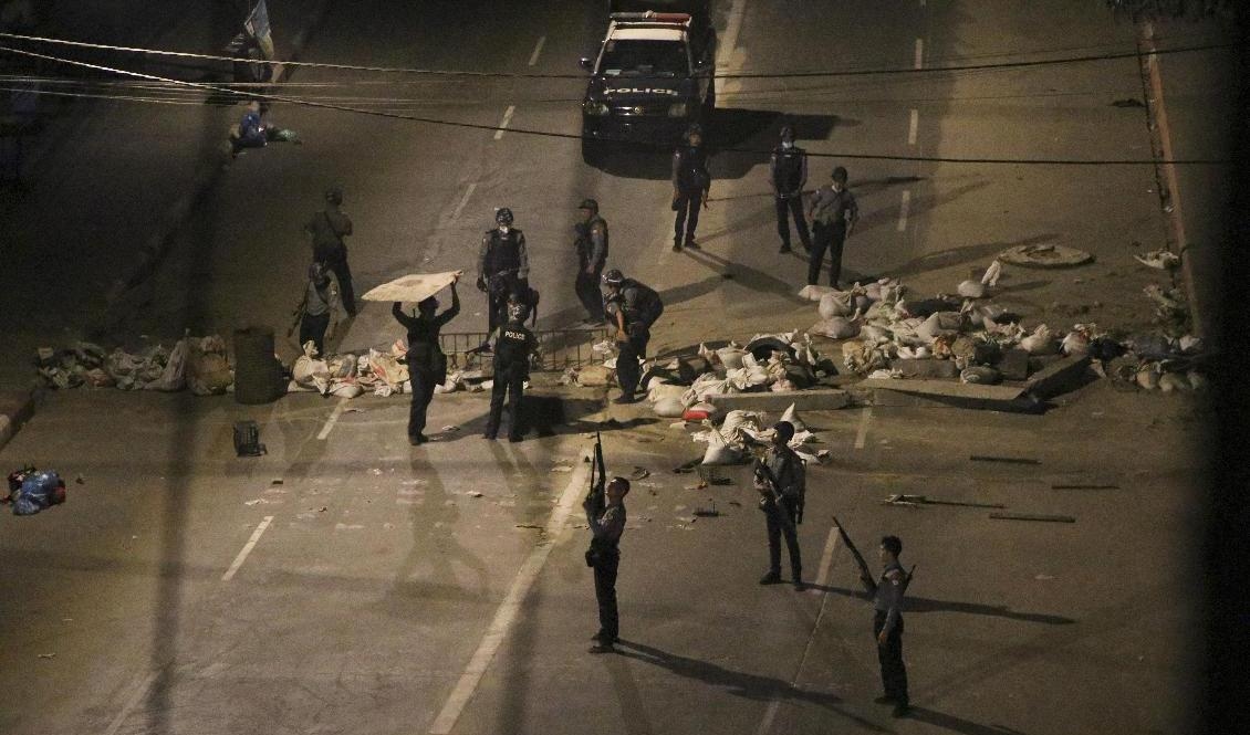 Poliser plockar bort barrikader i Rangoon efter helgens demonstrationer. Foto: AP/TT