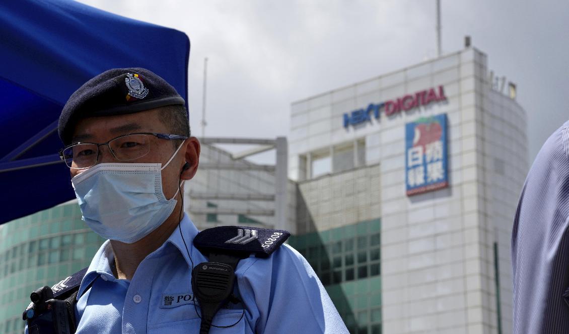 En polis står vakt utanför Apple Dailys redaktion i Hongkong. Foto: Kin Cheung/AP/TT