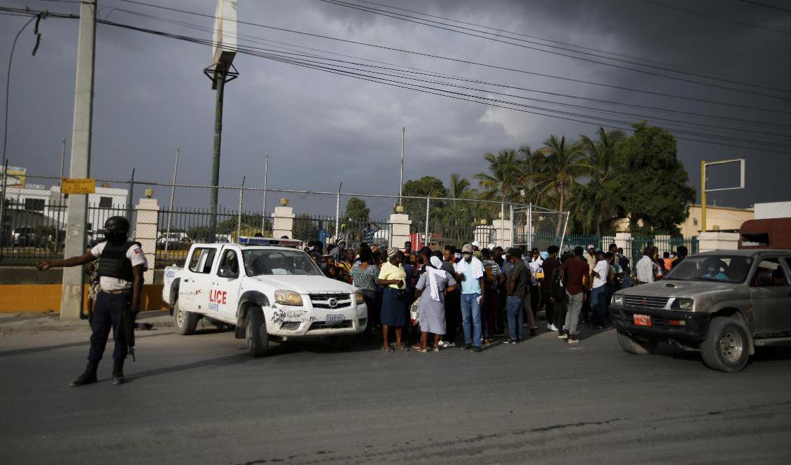 Haitisk polis stoppar folkmassor utanför USA:s ambassad i huvudstaden Port-au-Prince. Foto: Fernando Llano/AP/TT