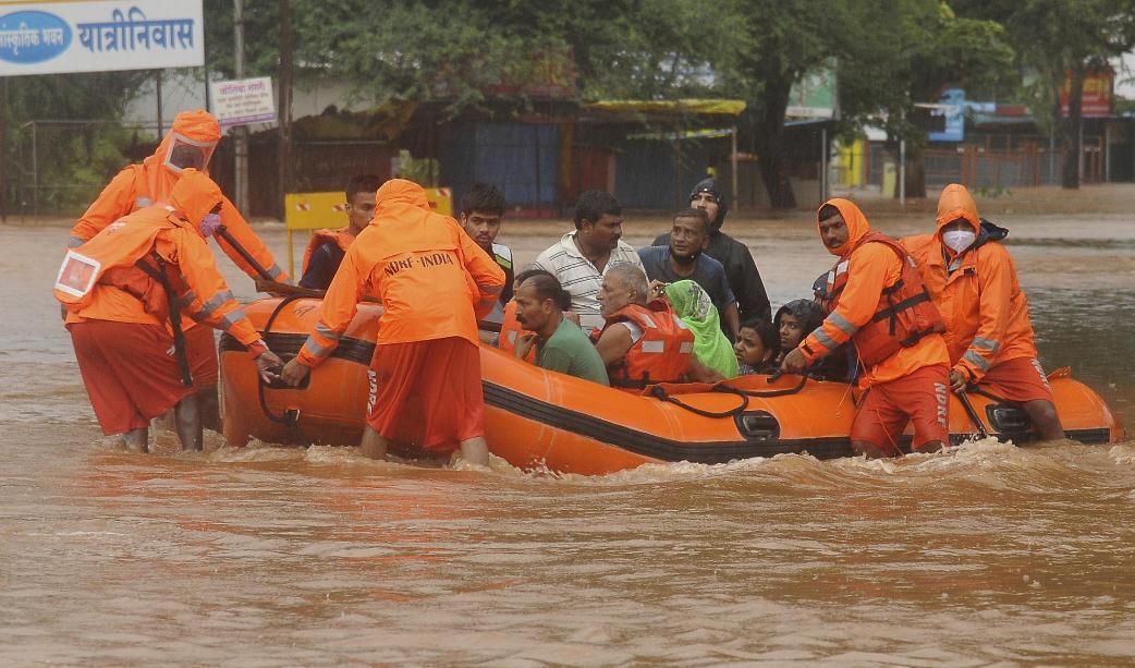 Räddningspersonal evakuerar människor som strandsatts i översvämningar i Kolhapur i västra Indien, efter kraftiga monsunregn. Foto: AP/TT