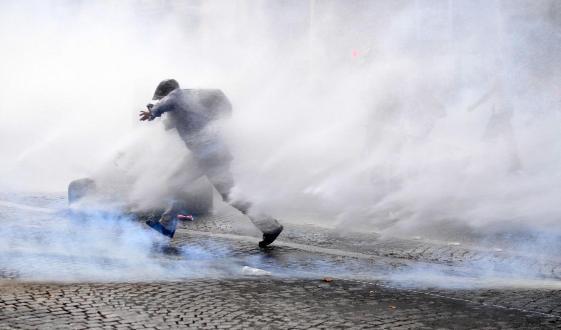 En fransman springer genom tårgas under protester mot Frankrikes obligatoriska vaccinationer för vissa yrkesgrupper och det obligatoriska vaccinationspasset. Den 21 juli 2021, Paris. Foto: Alain Jocard/AFP via Getty Images