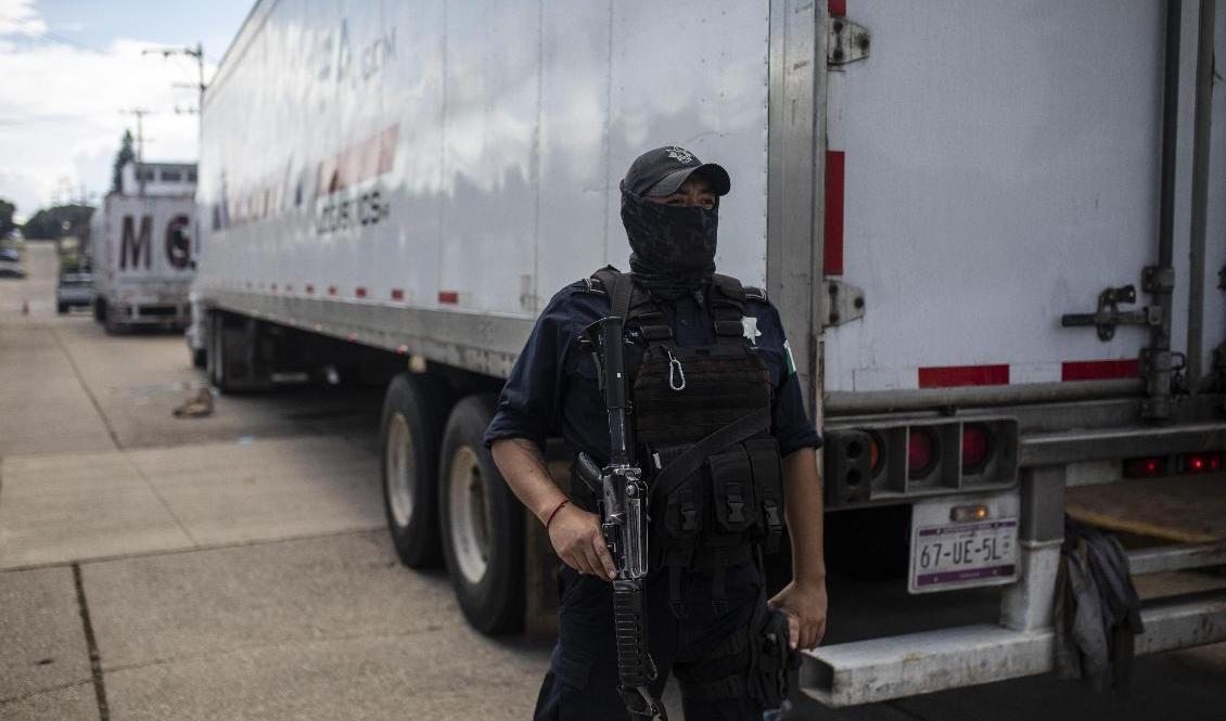 En polis vaktar en av de två lastbilarna i vilka runt 600 migranter försökte ta sig till USA. Foto: Felix Marquez/AP/TT