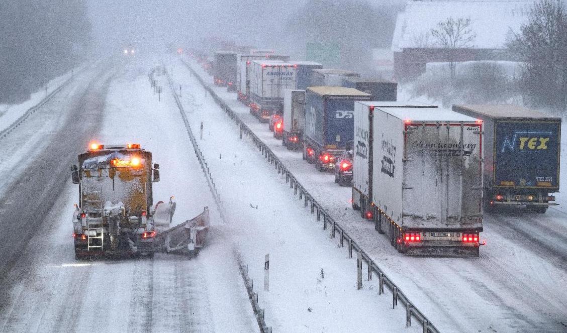 En plogbil kör norrut i södergående körfält, då lastbilar som inte kommer upp bogseras med hjullastare över Hallandsåsen på E6. Foto: Johan Nilsson/TT