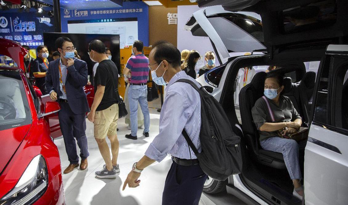 Besökare på en bilmässa i Peking provsitter Teslas elbilar. Arkivbild. Foto: Mark Schiefelbein/AP/TT