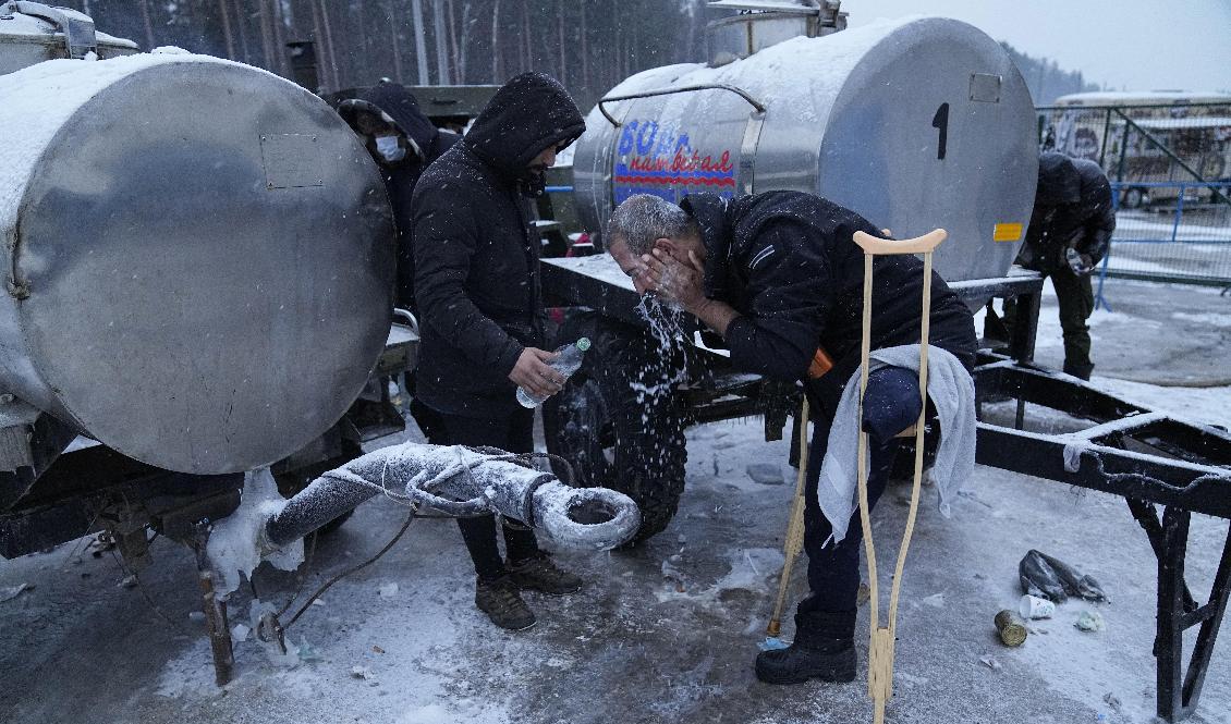 En migrant i Belarus tvättar ansiktet vid ett logistikcenter nära gränsen mot Polen.Arkivbild. Foto: Pavel Golovkin/AP/TT