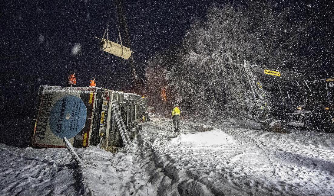 En lastbil som vält i halkan norr om Röke utanför Hässleholm bärgas i ymnigt snöfall på tisdagskvällen. Foto: Johan Nilsson/TT