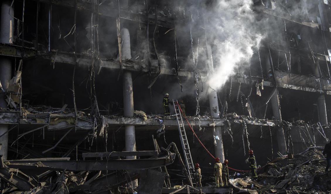 Brandmän vid det köpcenter i Kiev som anfölls av ryska bomber tidigare i veckan. Foto: Rodrigo Abd/AP/TT
