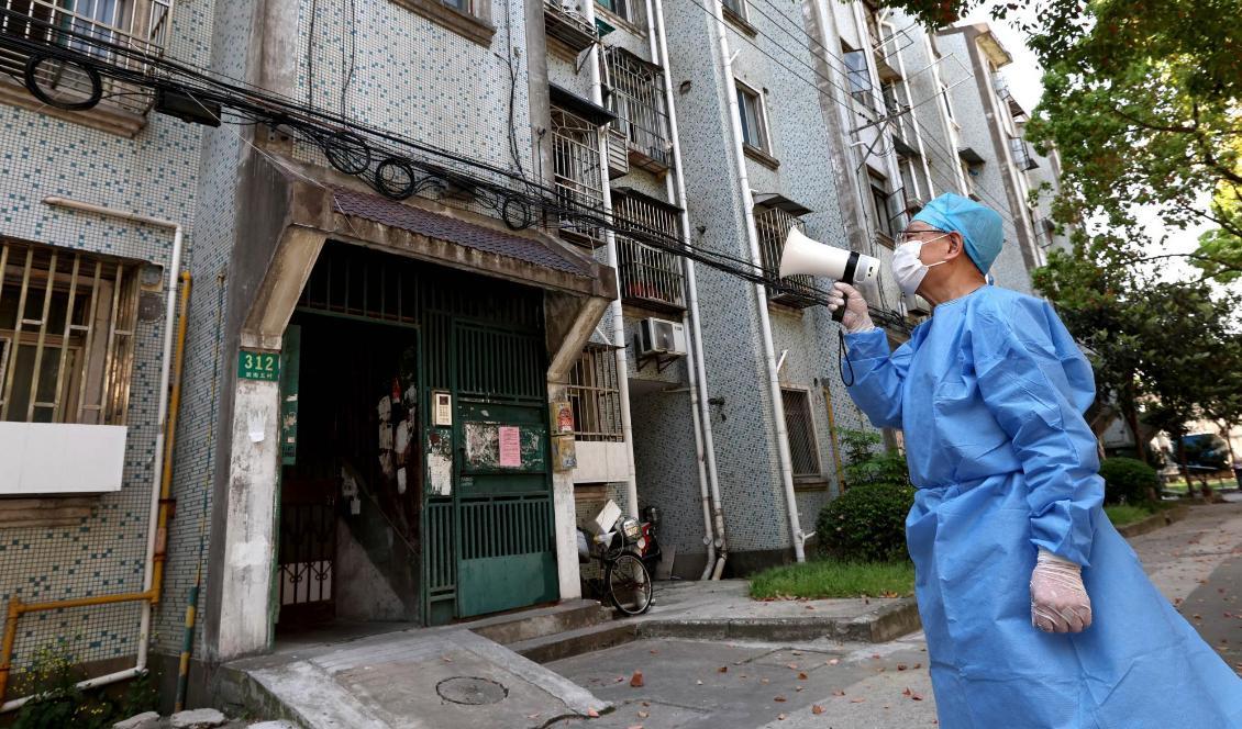 En volontär använder en megafon för att prata med invånare i ett bostadshus i Shanghai. Foto: Chen Jianli/Nya Kina/AP/TT