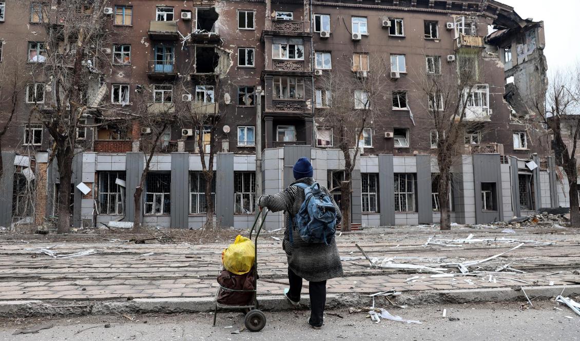 En boende i den belägrade ukrainska hamnstaden Mariupol tittar på en av de byggnader som förstörts sedan Rysslands anfallskrig inleddes den 24 februari. Foto: Alexei Alexandrov/AP/TT