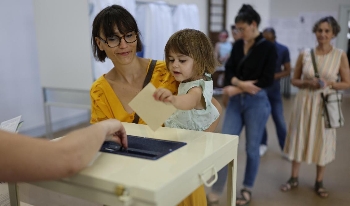 En flicka lägger ned sin mammas röst i Strasbourg i östra Frankrike i den första omgången av söndagens parlamentsval. Foto: Jean-Francois Badias/AP/TT