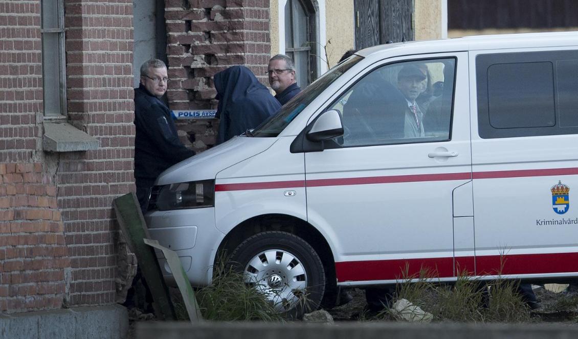 Nerijus Bilevicius (täckt i svart) i samband med att han fördes in den lada i Blomberg, Kinnekulle, där mordet på Lisa Holm begicks. Arkivbild. Foto: Björn Larsson Rosvall/TT