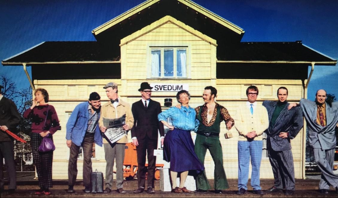 Några av de tjugotre märkliga karaktärer som vi får möta i filmen, uppradade framför det gula stationshuset i Svedum.