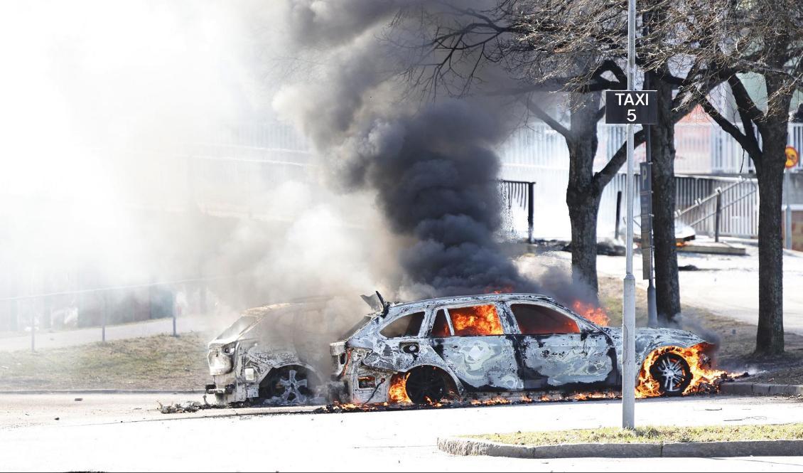 
Två bilar brinner i Ringdansens centrum i Navestad i Norrköping efter ett upplopp den 17 april i samband med att den danske-svenske politikern Rasmus Paludan aviserat om att tända eld på en koran. Foto: Stefan Jerrvång/TT                                            