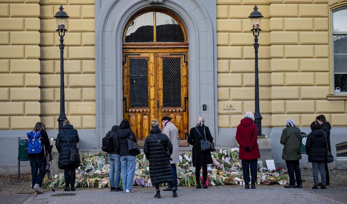 Malmö i mars 2022: En strid ström av sörjande passerar förbi de blommor, ljus och hälsningar som placerats trappan vid huvudingången utanför Latinskolan. Arkivbild. Foto: Johan Nilsson/TT