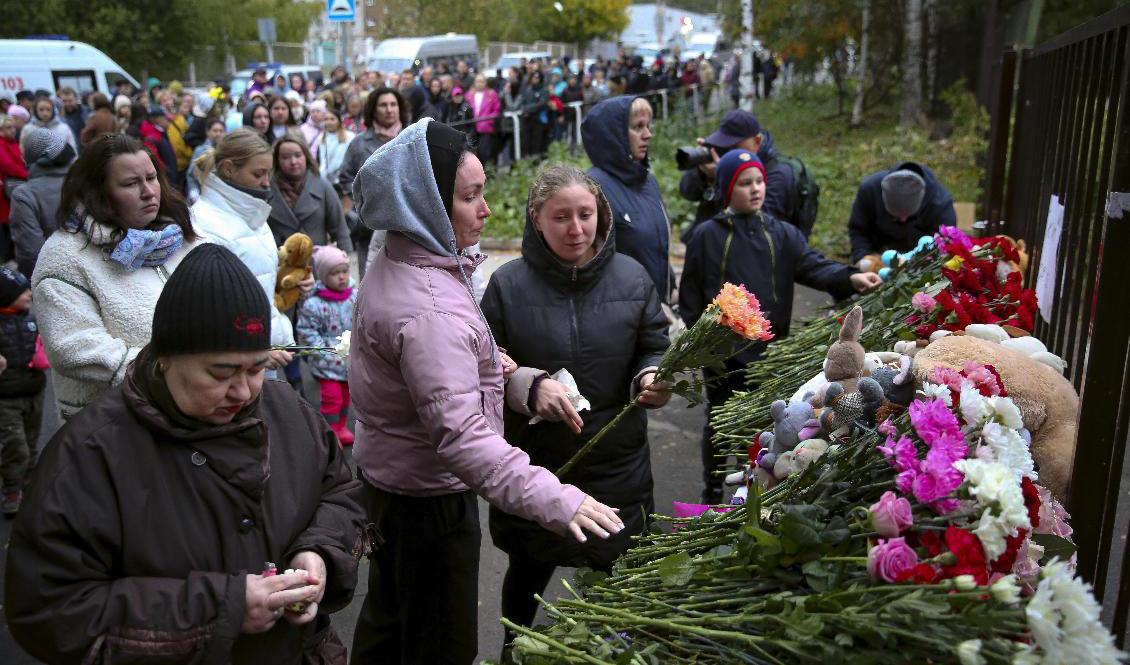 Människor lägger ner blommor utanför den skola i staden Izjevsk där minst 17 personer dödades. Foto: Sergei Kuznetsov/AP/TT