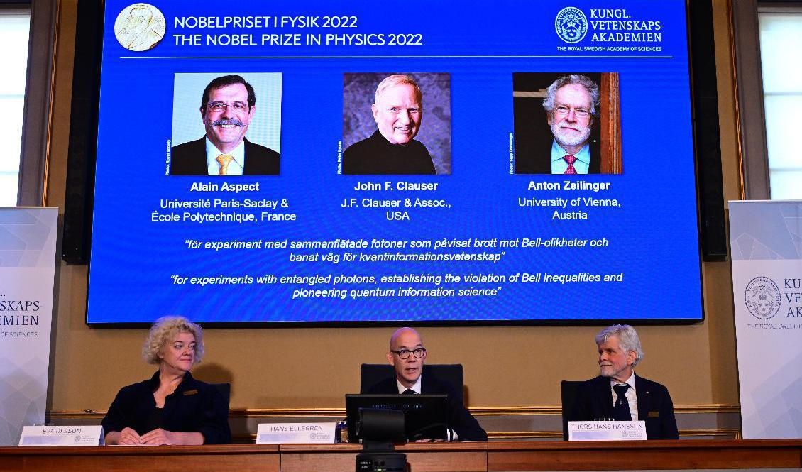 Hans Ellegren (mitten), Vetenskapsakademiens ständige sekreterare tillkännager vinnarna av 2022 års Nobelpris i fysik: Alain Aspect, John F Clauser och Anton Zeilinger. Till vänster sittande professor Eva Olsson och till höger professor Thors Hans Hansson. Foto: Jonas Ekströmer/TT