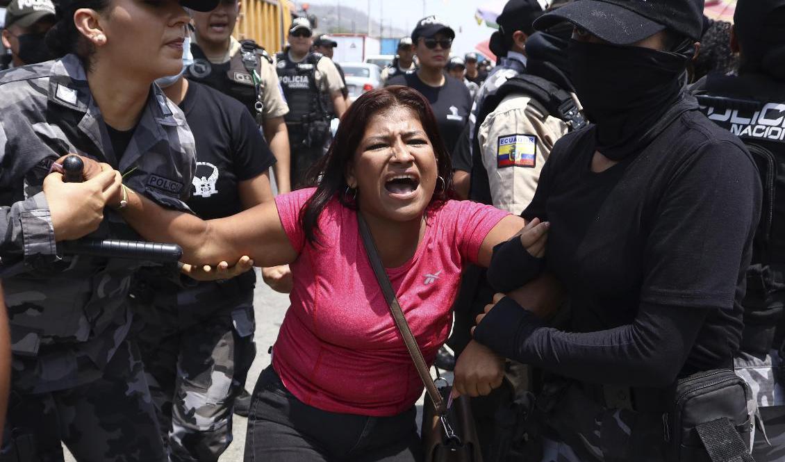 En anhörig till en fånge i Litoral-fängelset utanför Guayaquil omhändertas av poliser på torsdagen. Foto: Cesar Munoz/AP/TT