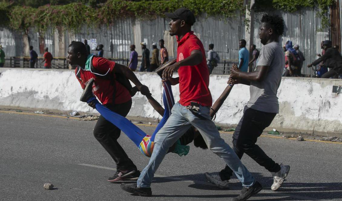 En kvinna som skjutits av polis bärs iväg i Haitis huvudstad Port-au-Prince den 10 oktober. Foto: Odelyn Joseph/AP/TT