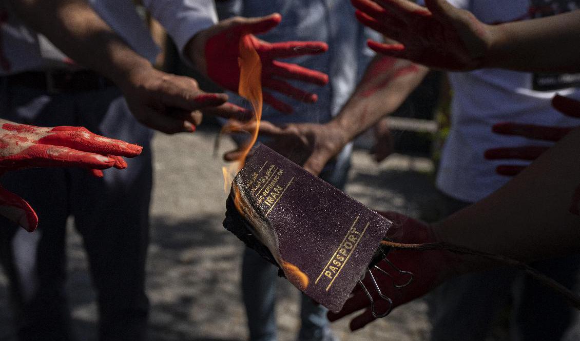 En iransk kvinna bränner sitt pass under en demonstration utanför Irans ambassad i Chiles huvudstad Santiago den 14 oktober. Foto: Esteban Felix/AP/TT