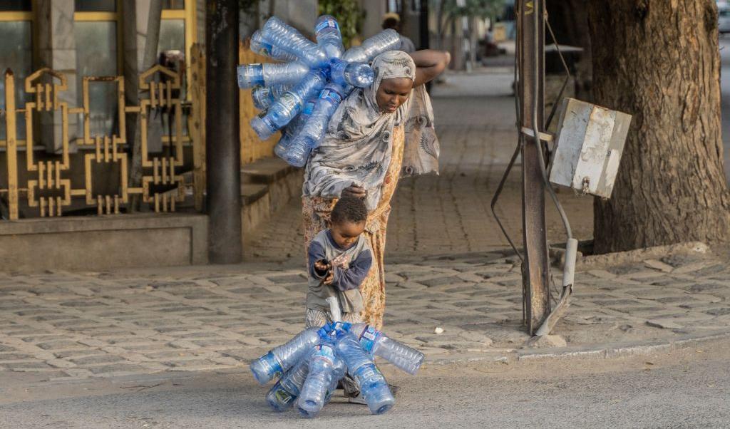 

En kvinna som bär på plastflaskor hjälper sitt barn med att göra detsamma. Detta sker i Dire Dawa, Etiopien. Foto: Amanuel Sileshi/AFP via Getty Images                                                                                        