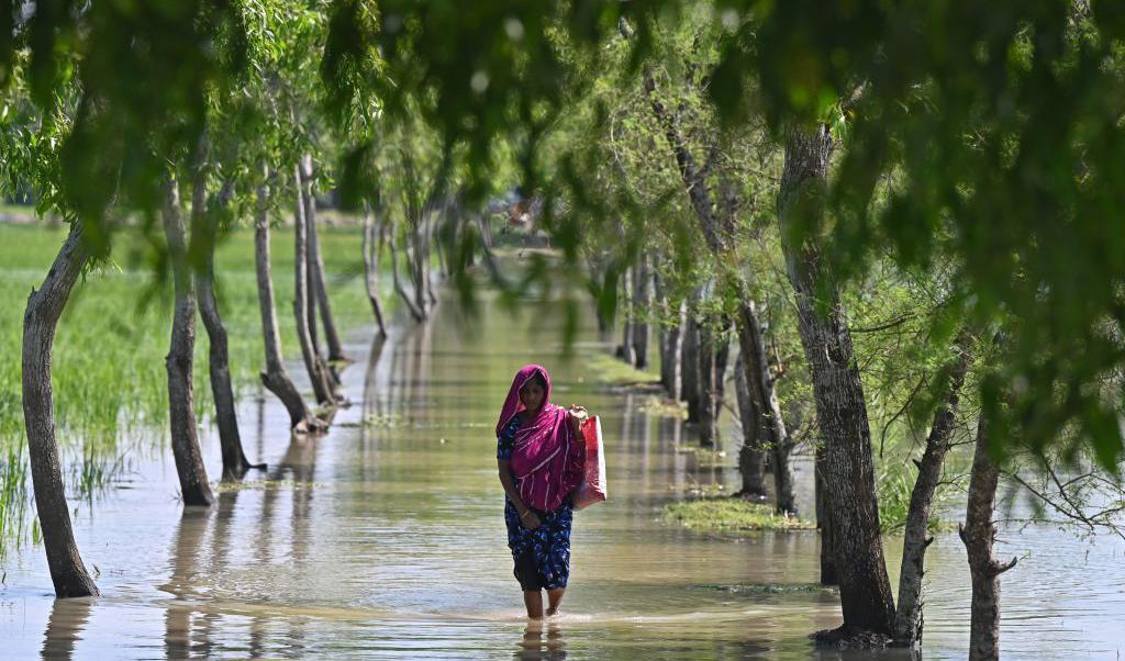 
En kvinna vadar genom vattnet som kom med cyklonen Sitrang i Kalapara, Bangladesh. Minst nio personen har dött och runt en miljon människor evakuerades från sina hem enligt officiella källor. Foto: Munir Uz Zaman/AFP via Getty Images                                            