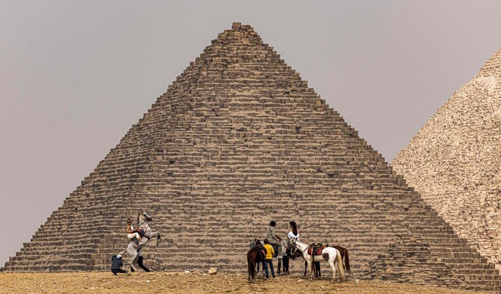 Ett gäng turister rider på sina hästar ut till pyramiderna på Giza-platån som ligger sydväst om Egyptens huvudstad Kairo.. Här står de framför den minsta av de tre, pyramiden Menkaura (Menkaure). Foto: Khaled Desouki/AFP via Getty Images