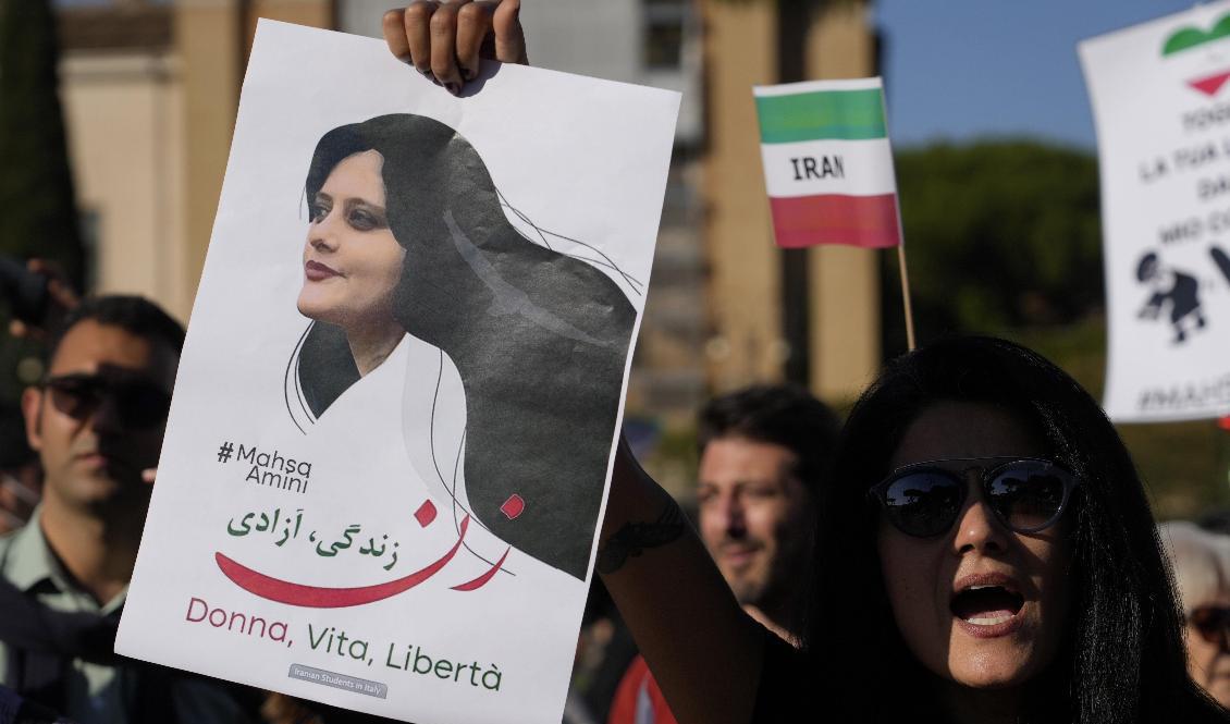 Demonstranter i Italiens huvudstad Rom håller upp en skylt med en bild på Mahsa Zhina Amini, som dog i den iranska moralpolisens förvar i september. Arkivbild. Foto: Gregorio Borgia/AP/TT