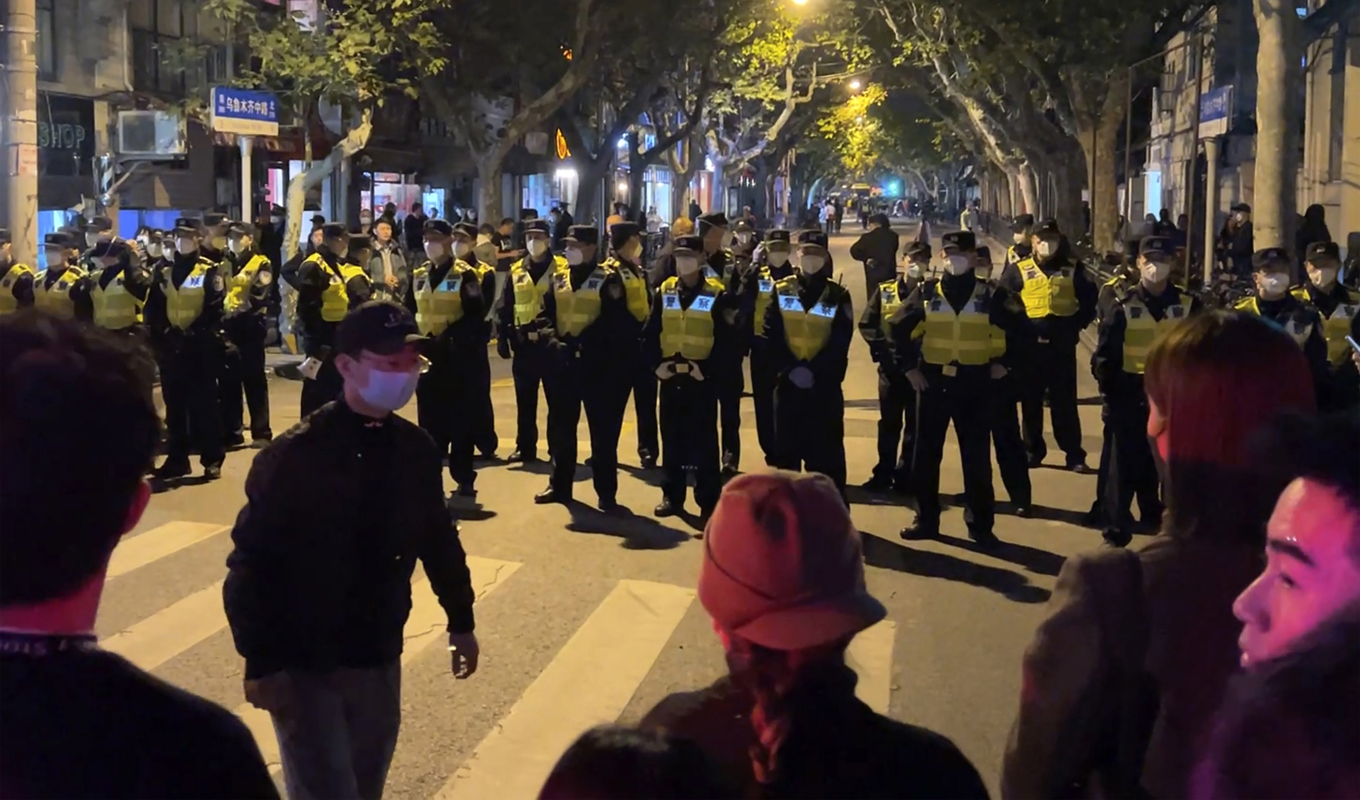 Kinesisk polis blockerar vägen till delar av den kinesiska staden Shanghai där demonstranter samlades under söndagen. Foto: AP/TT
