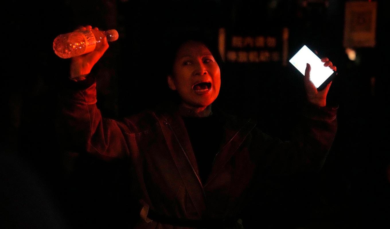 En kvinna protesterar i Peking mot regimens strikta "nollcovid"-politik. Foto: Ng Han Guan/AP/TT